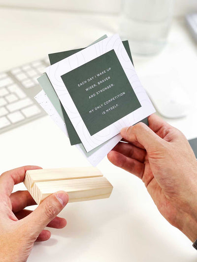 Positive green and white quote card with pine wood holder to display positive print pack on a desk