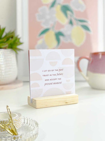 positive daily affirmation card back in wooden holder on aesthetic pink desk