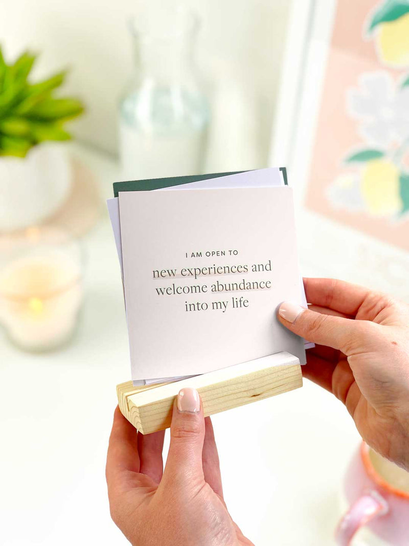 holding a set of positive affirmation cards with pine wood holder to display in the home or on an aesthetic office desk 